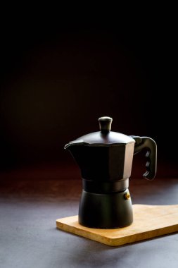 Espresso ya da sade kahve ve ahşap kesim tahtası ve koyu masa üzerinde moka demliği. Kahve konseptinin faydaları. 