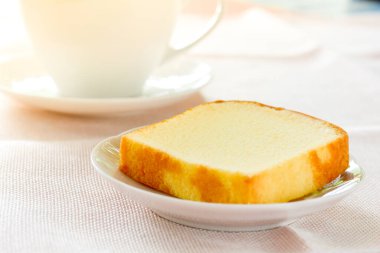 Beyaz tabakta bir parça tereyağlı kek ve bir fincan sade kahve. Kavramı gevşetme zamanı.