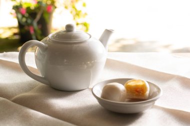 Beyaz kahve demliği yanında iki küçük ay çöreği ve klasik tonda bir masa. Ara zaman kavramı.