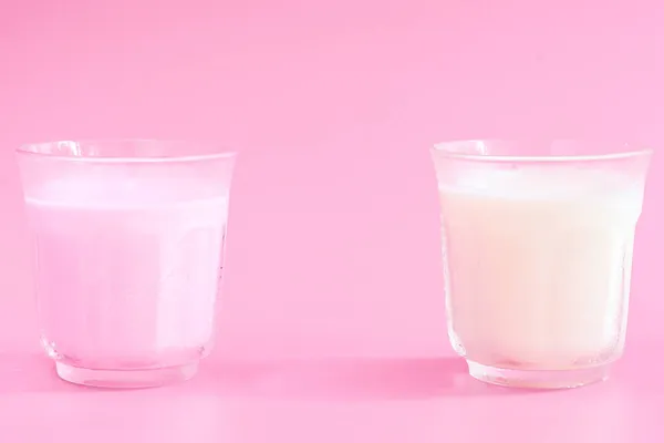 ピンク色の背景に冷たいピンクミルクのガラスは朝食に役立ちました 朝の飲み物のコンセプト — ストック写真