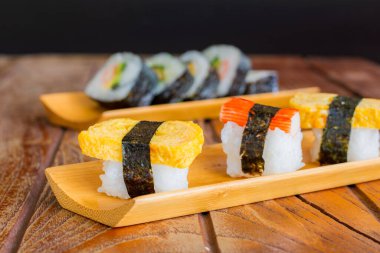 Tamagoyaki suşisi ya da pirinçli tatlı yumurta ve ahşap tepsi ve masada yosun dürümü. Lezzetli Japon yemekleri..
