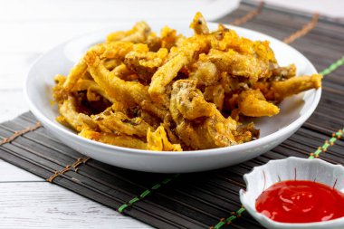 Abur cubur konsepti. Kızarmış istiridye mantarı, kırmızı acı biber soslu beyaz bir tabakta..