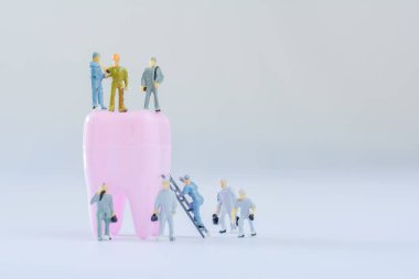 Minyatür insanlar, küçük model insan figürü kopyalama alanı olan temiz pembe dişli. Tıbbi ve diş konsepti. Diş bakımında takım çalışması.