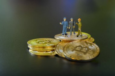 Minyatür insanlar takım çalışması, küçük model insan figürü altın Bitcoins 'in üzerinde duruyor ve metin için kopyalanacak yer var. Kripto para birimi veya dijital para kavramı.