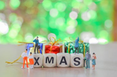 Bir grup aile minyatür insan, küçük model insan figürü yeşil bokeh ve kopyalama alanı olan alfabe ahşap kutunun üzerinde duruyor ve oturuyor..