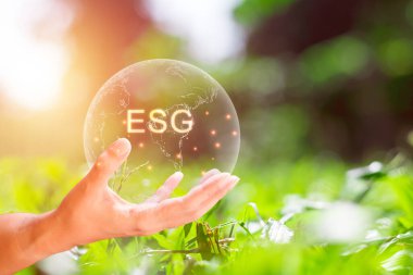 Çevre, sosyal ve yönetim (ESG) kavramı. Toprağın şeffaflığı ve yeşil arka planda ESG harfleri. Kirliliği azaltmak için yenilenebilir kaynak teknolojisini kullanmak