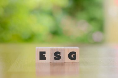 Çevre, sosyal ve yönetim (ESG) kavramı. Yeşil arka planda ESG harfiyle tahta küp bloğu. Kirliliği azaltmak için yenilenebilir kaynak teknolojisini kullanmak