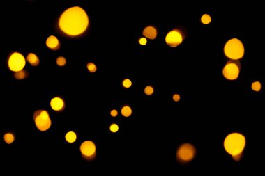 Koyu arkaplanda altın bokeh. Odaklanmamış altın ışıklar. Yeni yıl, Noel arkaplanı, soyut doku.