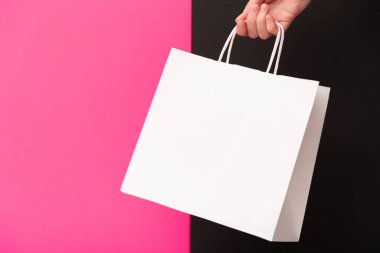 Pembe ve siyah arka planda beyaz, boş bir alışveriş çantası tutan kadın. Kara Cuma indirimi, geri dönüşüm, alışveriş ve ekoloji konsepti.