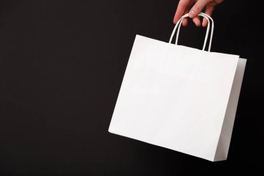 Siyah arka planda beyaz boş bir alışveriş çantası tutan kadın. Kara Cuma indirimi, geri dönüşüm, alışveriş ve ekoloji konsepti.