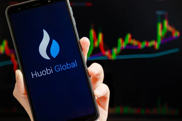 Ukraine, Odessa - October, 9 2021: Huobi Global mobile app running at smartphone screen with trading candlestick chart at background. Huobi Global is cryptocurrency exchange and trading platform. — Stockfoto