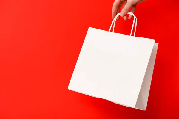 Mão Feminina Segurando Saco Compras Branco Branco Isolado Fundo Vermelho — Fotografia de Stock