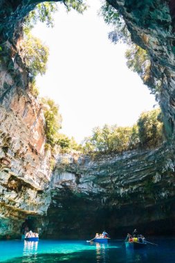 Melissani Mağarası, Cephalonia Adası, Yunanistan - 14 Temmuz 2019: Melissani Gölü 'nün ortasında turistli küçük tekneler ve fantastik mavi deniz suyu.