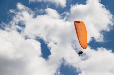 Mavi bulutlu gökyüzüne paraşütle atlayan çift portakal, güneşli bir gün..