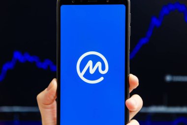 Ukrayna, Odessa - Ekim, 9, 2021: CoinMarketCap uygulaması akıllı telefon ekranında çalışan, arka planda şamdan şeması ticareti yapan cep telefonu. En güvenilir kripto para birimi veri yetkisine sahip dünyalar.