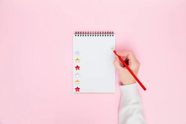 Scrivere a mano femminile in bianco vuoto aperto notebook a spirale con stelle isolate su sfondo rosa pastello. Posa piatta, spazio per la copia. Lavoro creativo, business, da fare lista o concetto di istruzione. — Foto Stock