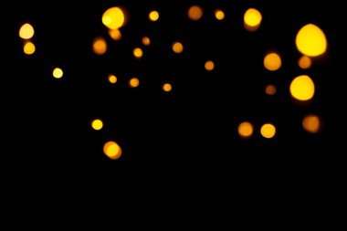 Koyu arkaplanda altın bokeh. Odaklanmamış altın ışıklar. Yeni yıl, Noel arkaplanı, soyut doku