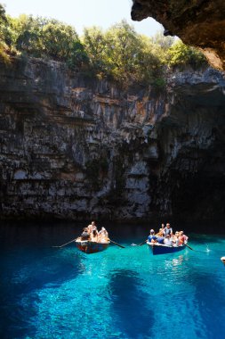 Melissani Mağarası, Cephalonia Adası, Yunanistan - 14 Temmuz 2019: Melissani Gölü 'nün ortasında turistli küçük tekneler ve fantastik mavi deniz suyu