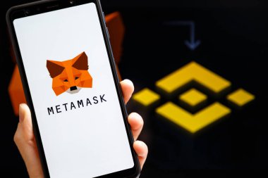 Ukrayna, Odessa - 9 Ekim 2021: MetaMaske uygulaması arka planda MetaMaske ve Binance logosu ile akıllı telefon ekranında çalışan el ele tutuşma uygulaması. MetaMaske Binance Akıllı Zincir kavramına bağlanıyor