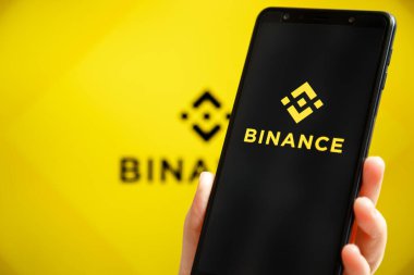 Ukrayna, Odessa - 9 Ekim 2021: Binance mobil uygulaması arkaplanda Binance logosu olan akıllı telefon ekranında çalışıyor. Binance dünyanın önde gelen kripto döviz ve ticaret platformlarından biri.
