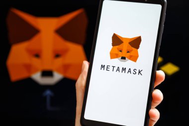 Ukrayna, Odessa - 9 Ekim 2021: MetaMaske uygulaması arka planda MetaMaske ve Binance logosu ile akıllı telefon ekranında çalışan el ele tutuşma uygulaması. MetaMaske Binance Akıllı Zincir kavramına bağlanıyor