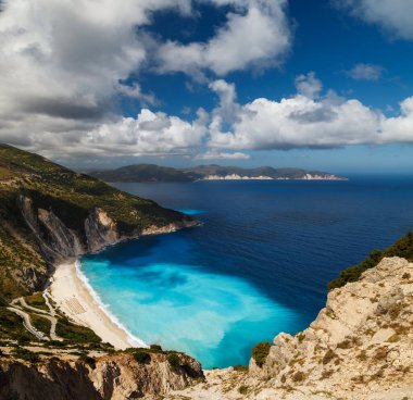 Myrtos Sahili 'nin en iyi panoramik manzarası ve muhteşem turkuaz ve mavi İyon Denizi suyu. Gökyüzü manzarası, ünlü ve son derece popüler Cephalonia, Yunanistan ve Avrupa 'daki yaz manzarası