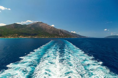 Yaz zamanı bir yolcu gemisinin arkasında açık deniz suyu izi. Feribot, Akdeniz 'in mavi ve berrak sularında Sefalonya Adası, Yunanistan' dan ayrılan bir iz bırakıyor.
