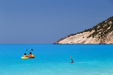 Myrtos Sahili, Cephalonia Adası, Yunanistan - 13 Temmuz 2019: Yunanistan 'daki Myrtos Sahili' nde insanlar mavi deniz suyunun tadını çıkarıyor ve yüzüyorlar.
