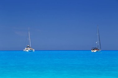 Beyaz yatlar Myrtos Sahili turkuaz ve mavi körfeze demirlemiş. Sefalonya Adası, Yunanistan ve Avrupa 'daki ünlü ve son derece popüler seyahat merkezinin yaz manzarası