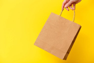 Sarı arka planda izole edilmiş kahverengi el çantasıyla gezen kadın. Kara Cuma indirimi, geri dönüşüm, alışveriş ve ekoloji konsepti
