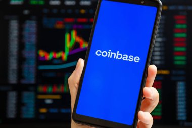 Ukrayna, Odessa - 9 Ekim 2021: Arkaplanda ticaret sayfası olan akıllı telefon ekranında çalışan Coinbase uygulaması ile el ele tutuşma cep telefonu. Para tabanlı Amerikan kripto döviz ve ticaret platformu