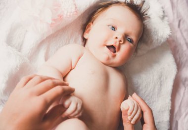 Yatağa uzanmış gülümseyen güzel bir kızın yakın plan portresi. Anne yeni doğmuş bebeğini kucağında tutuyor. Küçük kız ve anne.