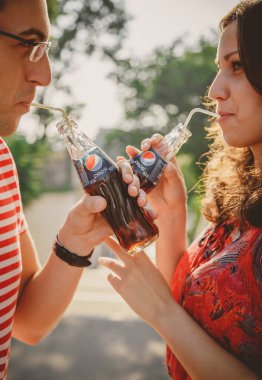 ODESSA, UKRAINE - 15 Ekim 2014: Dışarıdaki mutlu genç çiftin soğuk Pepsi 'yi pipetle içerek birbirlerine bakmaları.