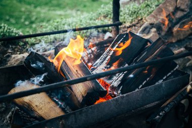 Metal brazier 'ın içinde yakacak odun yanıyor. Yaz mevsiminde dışarıda barbekü hazırlığı.