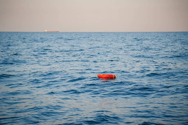 Safety equipment, life buoy or rescue buoy ring with a rope floating in blue sea to rescue people. Yachting, marine background.