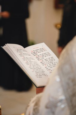 Christening in the church, priest is reading a prayer from the Bible. Details in the orthodox christian church.