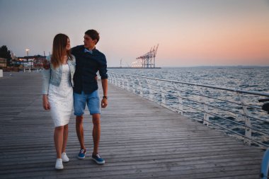 Bir çift genç hippi aşığı yaz mevsiminde güneşin doğuşunda sahilde birbirlerine sarılıyorlar..