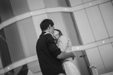 Sarılıp öpüşen çift, gündoğumunda gökyüzünde yaz zamanı, şehir arka planında..