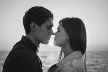 Yaz mevsiminde güneşin doğuşunda kumsalda kucaklaşan bir çiftin yakın çekimi..