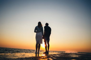 Çiftin silueti iskelede duruyor, yaz mevsiminde güneşin doğuşunu izliyorlar..