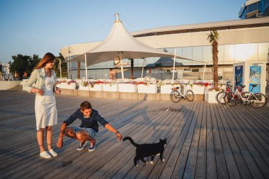 ODESSA, UKRAINE - Ağustos 06, 2015: Genç çift yaz mevsiminde plajda bir kediyle oynuyor.