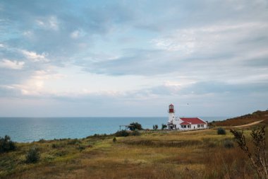 Deniz kıyısındaki eski beyaz deniz feneri, yaz manzarası.