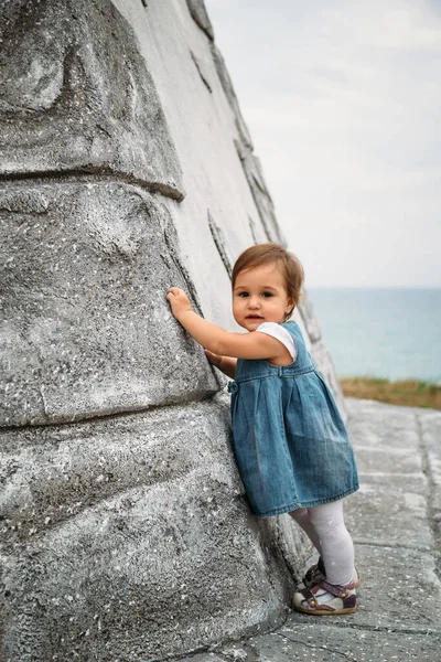 Eski Deniz Fenerinin Duvarında Duran Kot Elbiseli Mutlu Küçük Kız — Stok fotoğraf