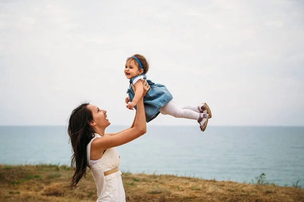 Happy Young Mother Playing Small Daughter Throwing Air Outdoors Background — Stockfoto