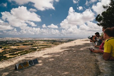 MDINA, MALTA - SEPTEMBER, 15 2018: A group of tourists looking at a beautiful panoramic view of Malta island from the top of Bastion Square at Mdina, ancient capital of Malta, fortified medieval town.
