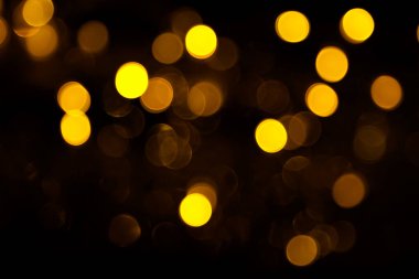 Abstract gold bokeh on black background. Defocused yellow lights, abstract texture.