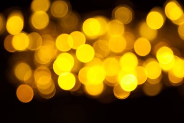 Abstract gold bokeh on black background. Defocused yellow lights, abstract texture.