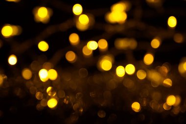 Abstract gold bokeh on black background. Defocused yellow lights, abstract texture.