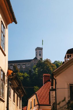 A view at Ljubljana Castle tower from a beautiful quiet narrow street with orange tiled roofs without people in the old centre of Ljubljana, Slovenia.