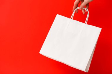 Kırmızı arka planda beyaz boş bir alışveriş çantası tutan kadın. Kara Cuma indirimi, geri dönüşüm, alışveriş ve ekoloji konsepti